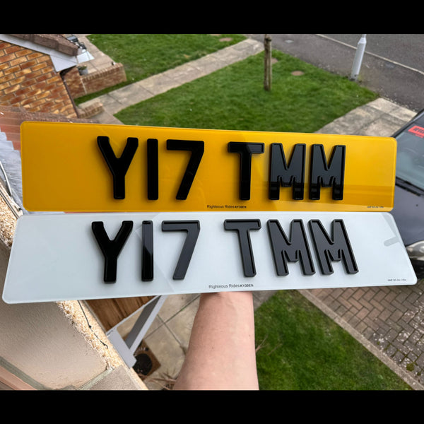 Two license plates with Ghost style text held up  to highlight digit design